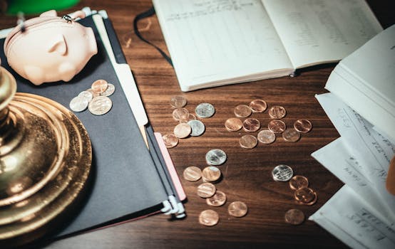 From above coins scattered on desk near financial papers and lovely pig wallet in accountant office